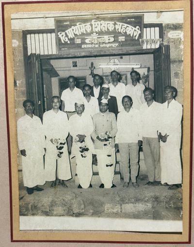 A group felicitation photograph, garlands being presented, outside 'The Prathmik Shikshak Sahakari Bank Ltd., Kolhapur' (the Primary Teachers' Cooperative Bank) — consistent with newspaper mentions of his involvement in the teachers' cooperative bank.