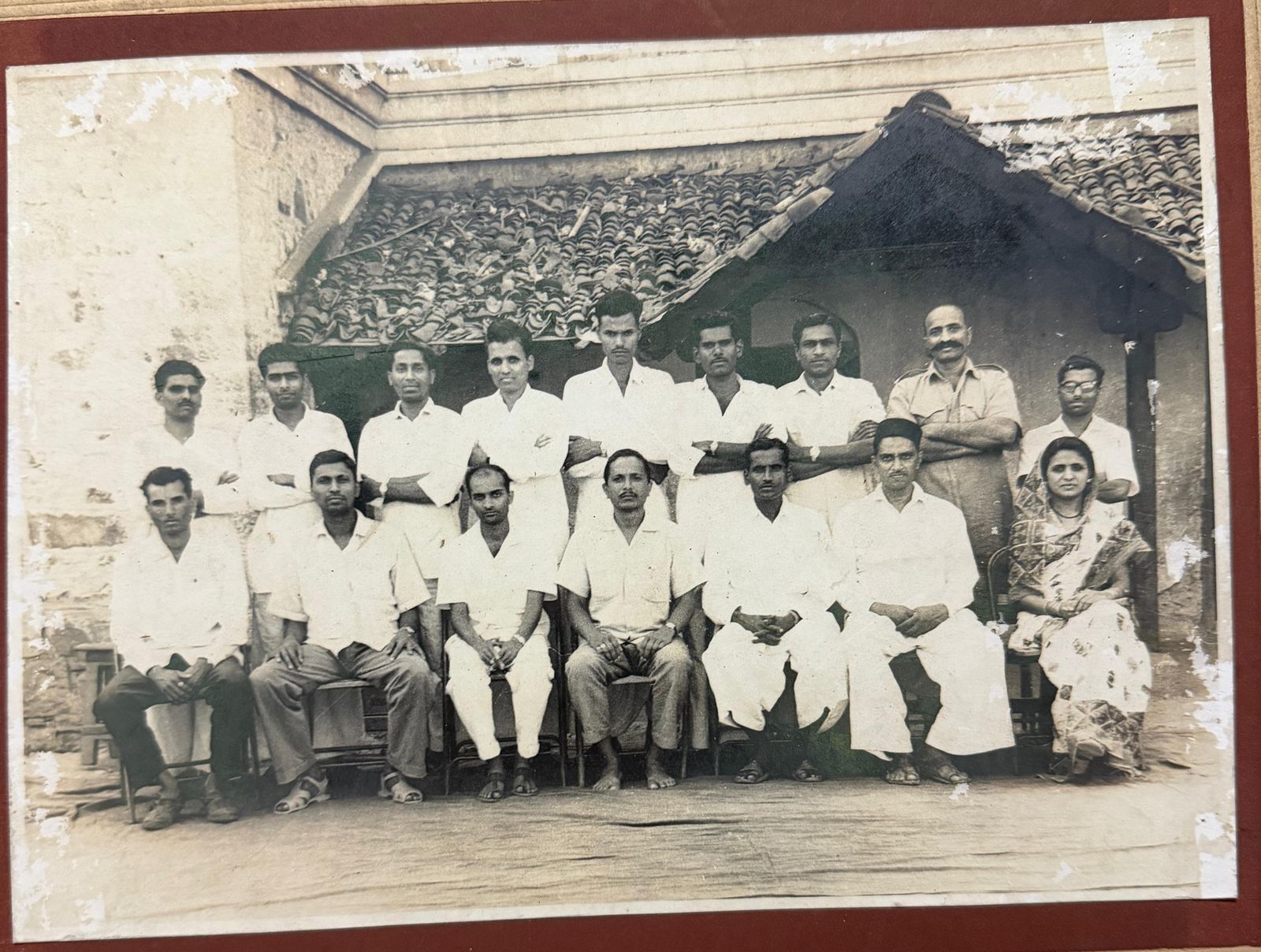An old, undated group photograph believed to show school staff and colleagues outside a tiled-roof building.